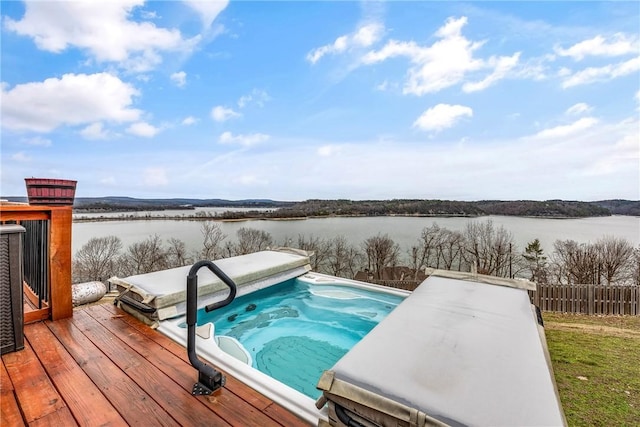 view of swimming pool with a deck with water view and a covered hot tub