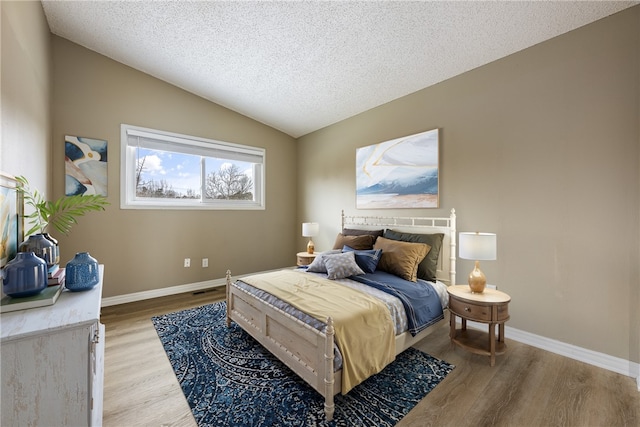 bedroom featuring vaulted ceiling, a textured ceiling, and light wood-type flooring