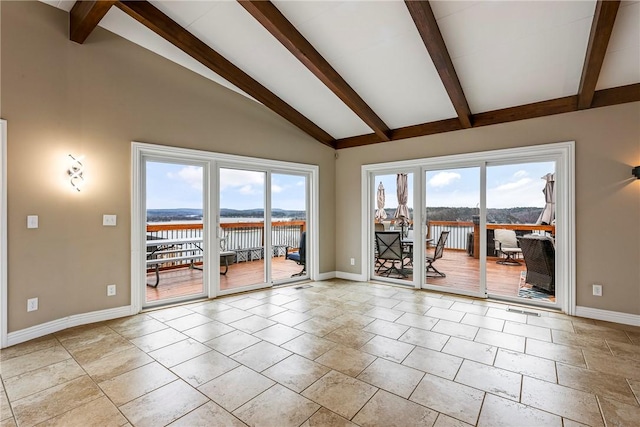 unfurnished room featuring beam ceiling, high vaulted ceiling, and a water view