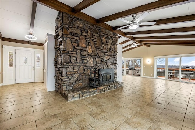 unfurnished living room with ceiling fan, a wood stove, and vaulted ceiling with beams