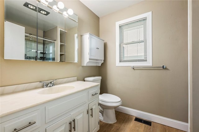 bathroom with vanity, hardwood / wood-style floors, a shower with door, and toilet