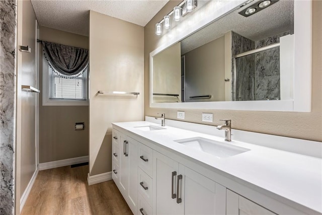 bathroom featuring wood-type flooring, vanity, a textured ceiling, and a shower with shower door