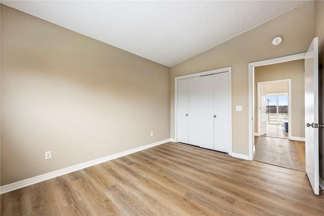 unfurnished bedroom featuring lofted ceiling, light hardwood / wood-style floors, and a closet