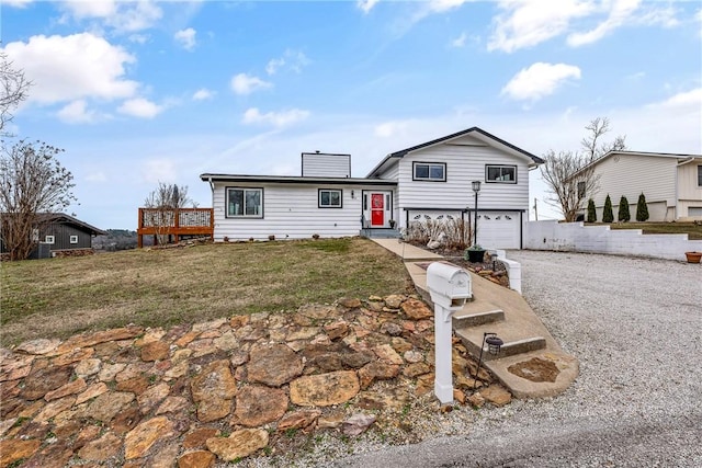 view of front facade featuring a garage, a wooden deck, and a front yard