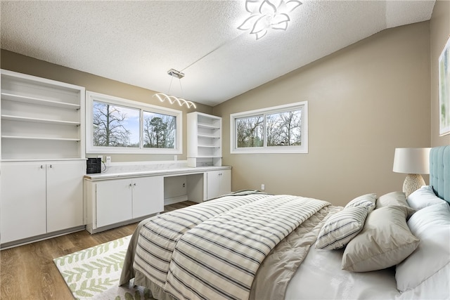 bedroom with lofted ceiling, light hardwood / wood-style floors, and a textured ceiling