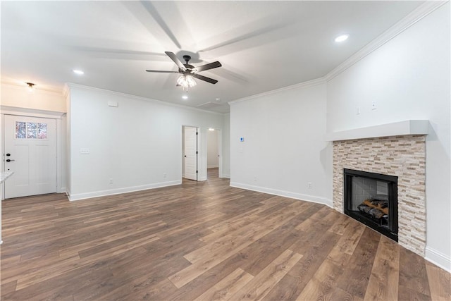 unfurnished living room featuring hardwood / wood-style flooring, ceiling fan, a stone fireplace, and crown molding