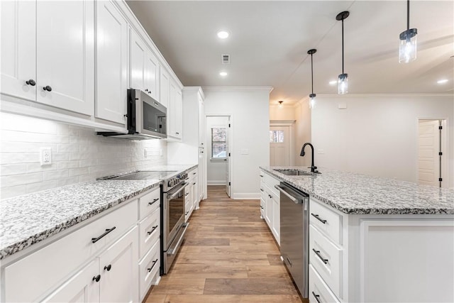 kitchen with sink, white cabinetry, decorative light fixtures, stainless steel appliances, and a kitchen island with sink