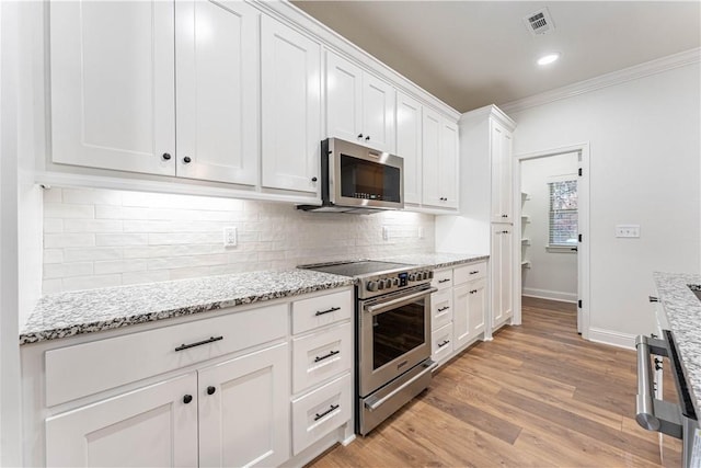 kitchen with white cabinetry, light stone counters, light hardwood / wood-style flooring, appliances with stainless steel finishes, and decorative backsplash