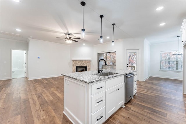 kitchen with hanging light fixtures, sink, a center island with sink, and white cabinets