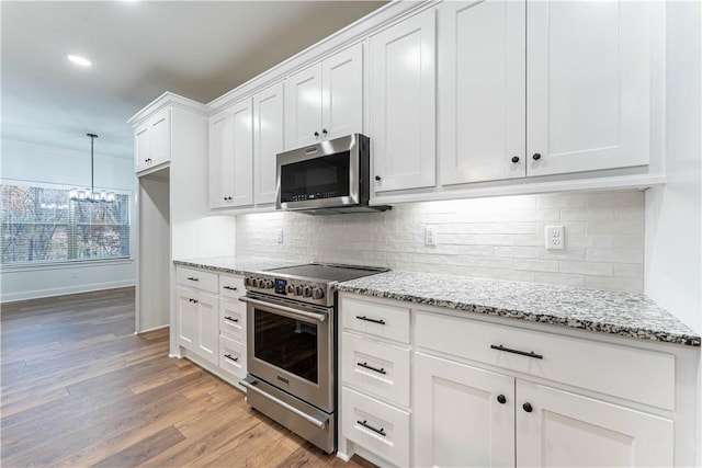 kitchen featuring pendant lighting, white cabinetry, stainless steel appliances, light stone countertops, and light hardwood / wood-style floors