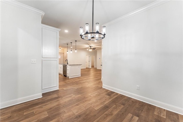 unfurnished dining area with crown molding, wood-type flooring, sink, and ceiling fan with notable chandelier