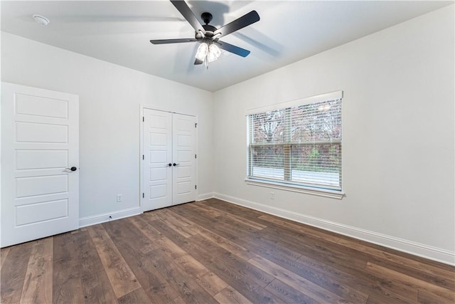 unfurnished bedroom featuring dark wood-type flooring, ceiling fan, and a closet