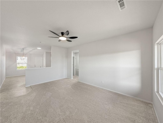 empty room featuring ceiling fan, light carpet, and a textured ceiling