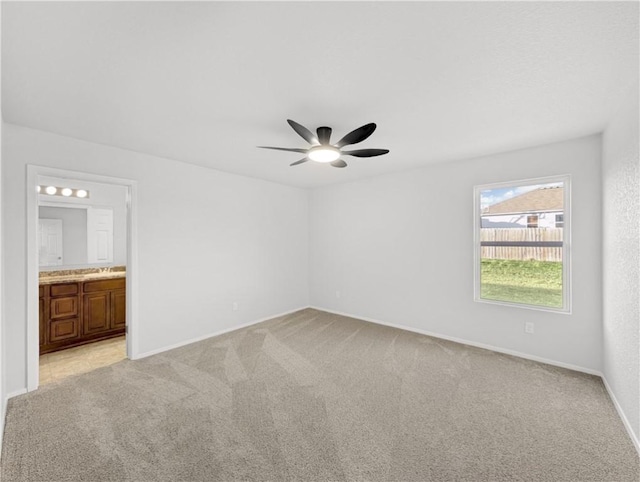 unfurnished bedroom with ceiling fan, light colored carpet, and ensuite bathroom