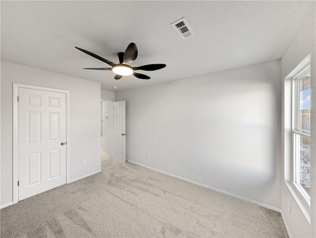 carpeted spare room featuring ceiling fan, plenty of natural light, and a textured ceiling