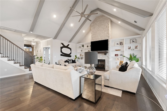 living room with dark wood-type flooring, beam ceiling, high vaulted ceiling, a fireplace, and ceiling fan with notable chandelier