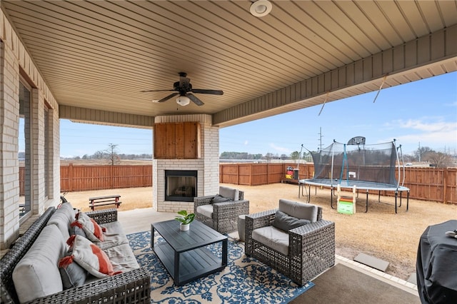 view of patio / terrace featuring a trampoline and an outdoor living space with a fireplace