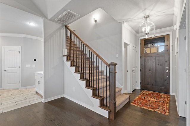 foyer entrance with hardwood / wood-style flooring, ornamental molding, and a chandelier