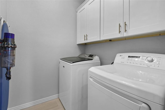 washroom with washer and clothes dryer, cabinets, and light wood-type flooring