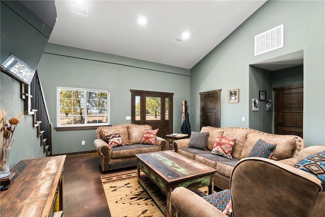 living area with stairway, visible vents, and high vaulted ceiling