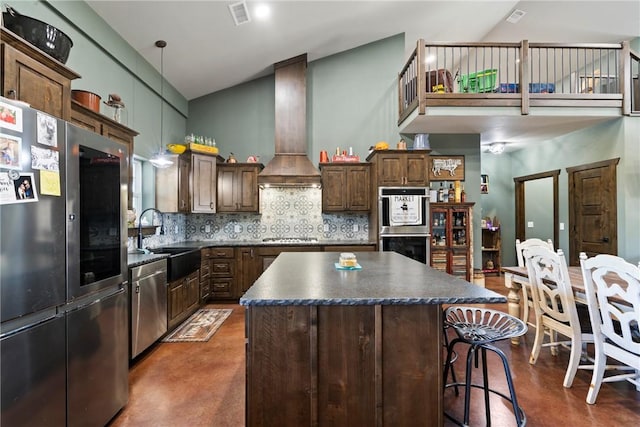 kitchen with custom exhaust hood, stainless steel appliances, dark countertops, visible vents, and a sink