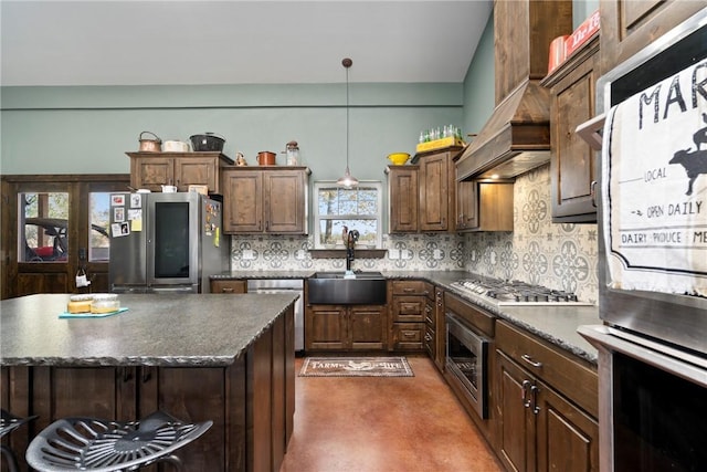 kitchen featuring a sink, appliances with stainless steel finishes, pendant lighting, dark countertops, and tasteful backsplash