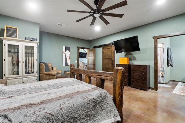 bedroom with visible vents, a barn door, concrete floors, baseboards, and ceiling fan