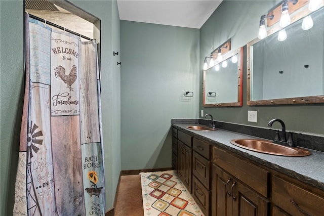 full bath featuring double vanity, baseboards, and a sink