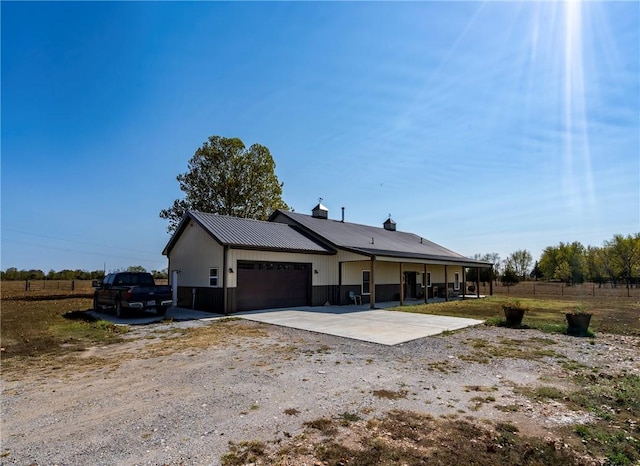 back of property with an attached garage, fence, driveway, and metal roof