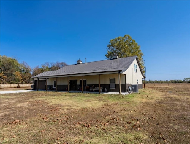 back of property with a garage, a patio area, central air condition unit, and metal roof