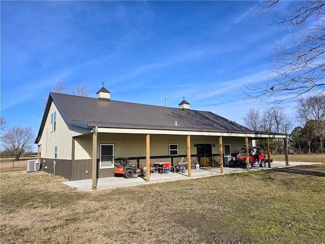 back of property with a yard, central air condition unit, and metal roof