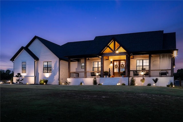 view of front facade with central AC, covered porch, and a lawn