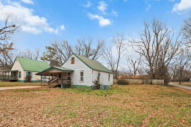 view of side of home with a porch, a yard, and central air condition unit