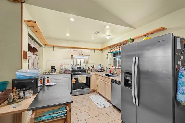 kitchen with sink, light tile patterned floors, vaulted ceiling, and stainless steel appliances