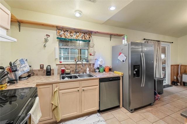 kitchen featuring sink, decorative backsplash, light tile patterned floors, and appliances with stainless steel finishes