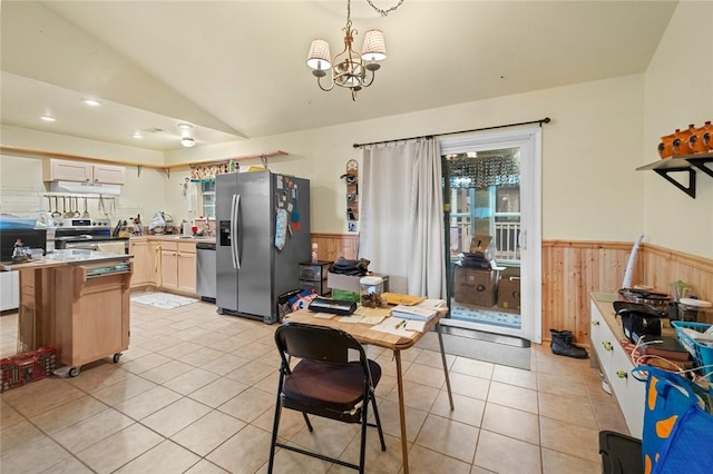 kitchen with lofted ceiling, light tile patterned floors, appliances with stainless steel finishes, decorative light fixtures, and exhaust hood