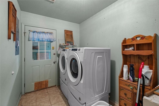 laundry area with a textured ceiling, washer and dryer, and light tile patterned floors