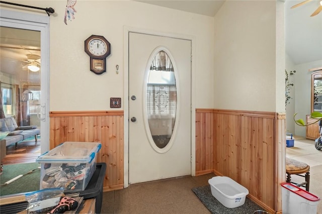 foyer featuring ceiling fan and wood walls