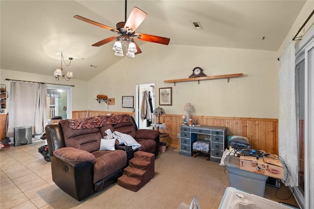 living room with light tile patterned floors, ceiling fan with notable chandelier, vaulted ceiling, and wood walls