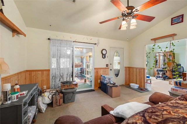 living room featuring vaulted ceiling, light carpet, ceiling fan, and wood walls