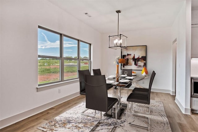 dining space with a notable chandelier and light hardwood / wood-style flooring