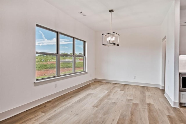 unfurnished dining area with a chandelier and light hardwood / wood-style flooring