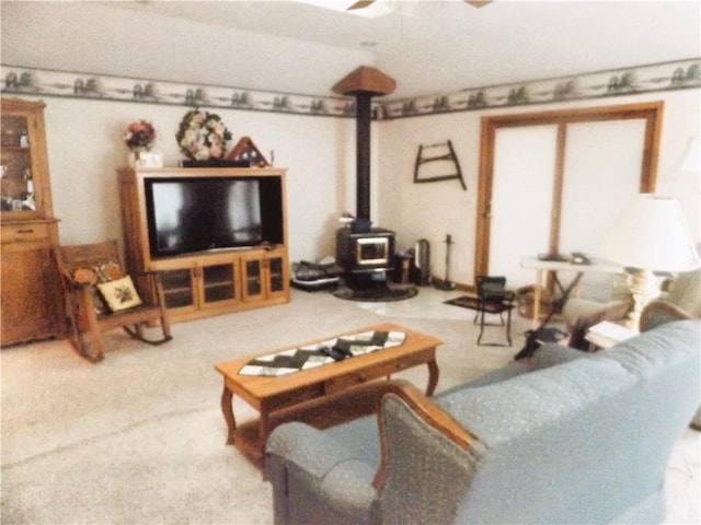 living room with carpet flooring, ceiling fan, and a wood stove