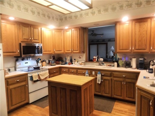 kitchen with sink, a center island, white electric range oven, ceiling fan, and light wood-type flooring