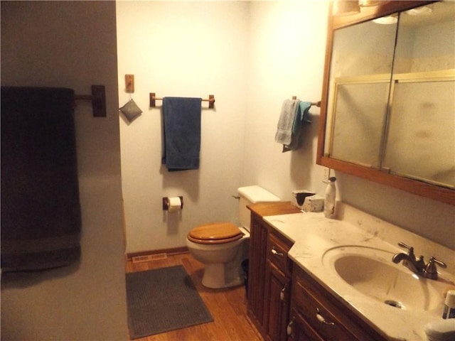 bathroom with hardwood / wood-style flooring, vanity, toilet, and a shower with door