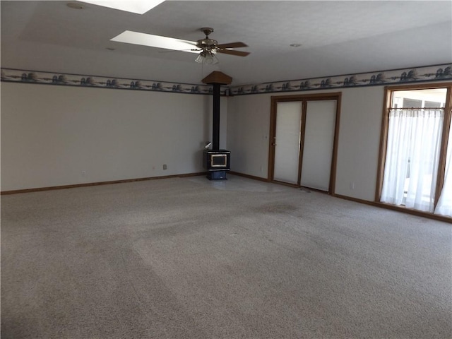 82 Baypoint Dr, Mountain Home, AR 72653 - unfurnished room featuring a wood stove, ceiling fan, lofted ceiling with skylight, and light carpet