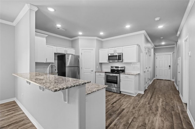 kitchen featuring a kitchen bar, white cabinetry, light stone counters, appliances with stainless steel finishes, and kitchen peninsula