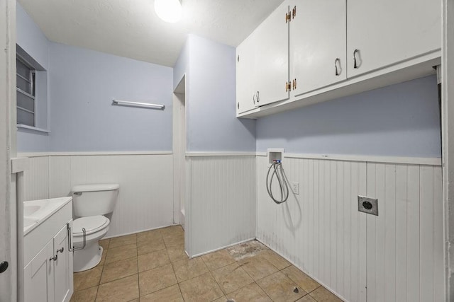 clothes washing area with hookup for an electric dryer, wainscoting, hookup for a washing machine, and light tile patterned floors