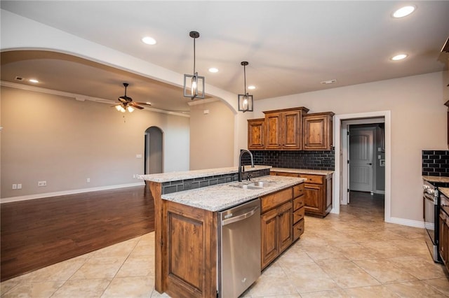 kitchen featuring sink, decorative light fixtures, appliances with stainless steel finishes, ceiling fan, and a kitchen island with sink