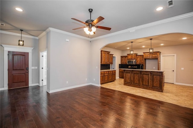 kitchen featuring hanging light fixtures, a center island, ceiling fan, light hardwood / wood-style floors, and crown molding